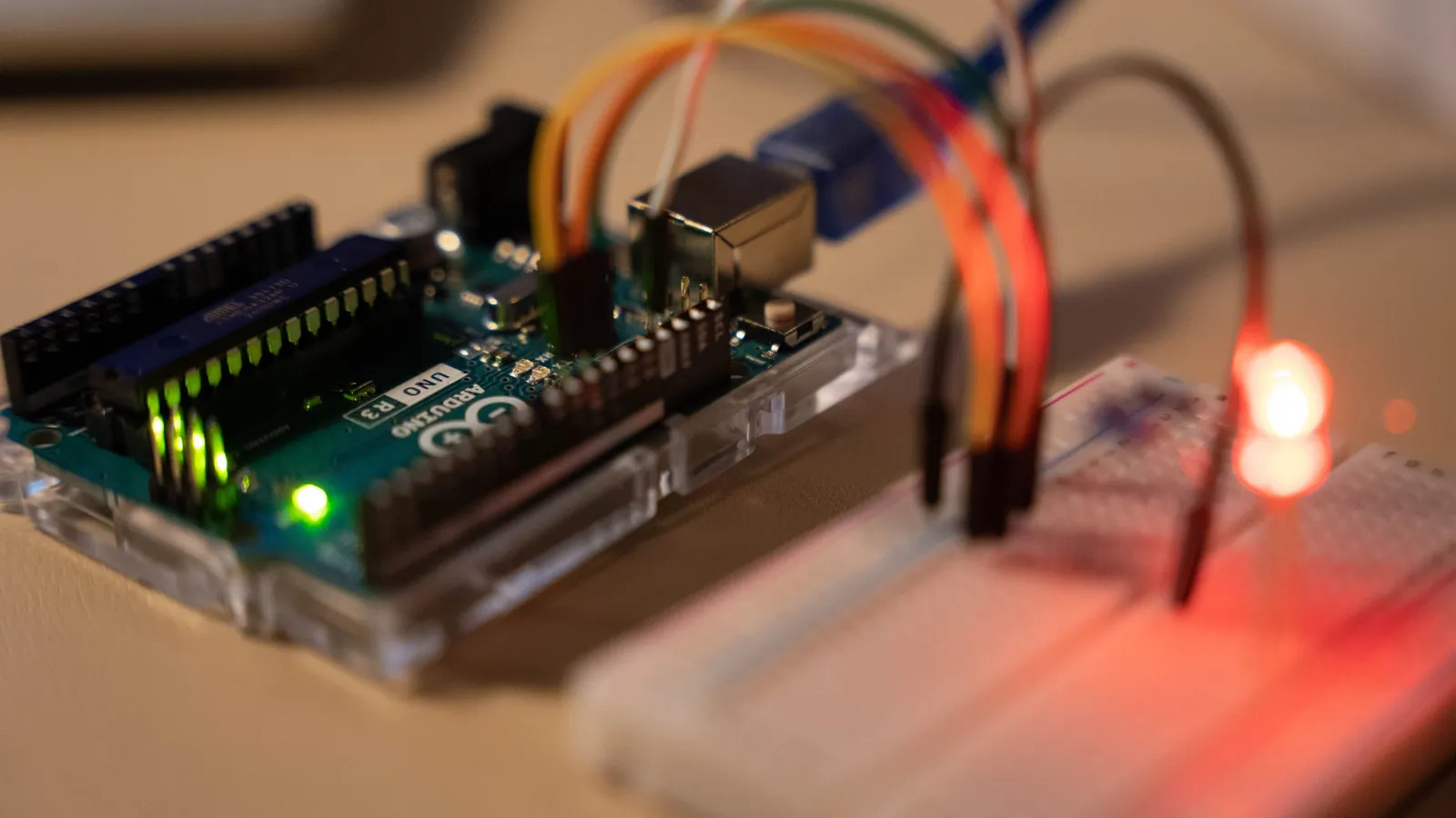 Una scheda Arduino Uno collegata con cavetti colorati a una breadboard, con un LED rosso acceso
