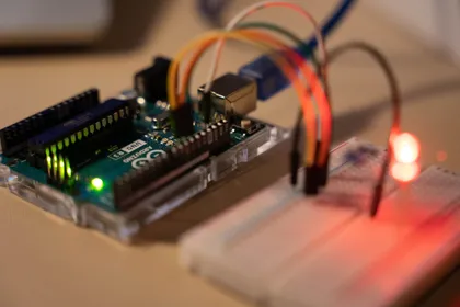 Una scheda Arduino Uno collegata con cavetti colorati a una breadboard, con un LED rosso acceso